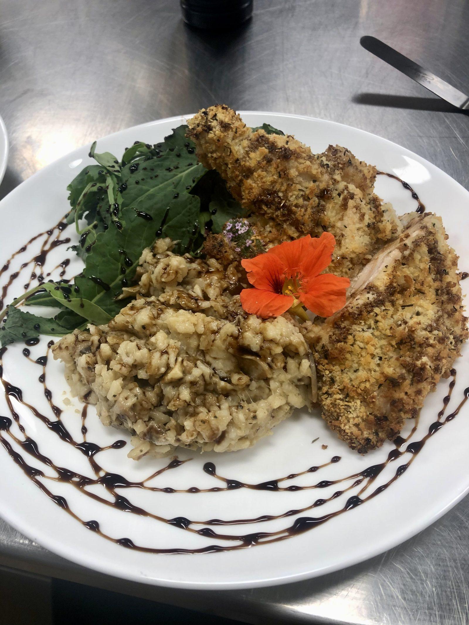 Herb-crusted entree with mushroom risotto and edible flowers